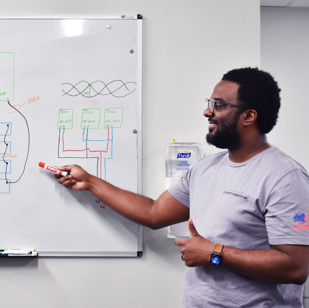 Photo of a Current Connected employee using a whiteboard to explain electrical concepts.